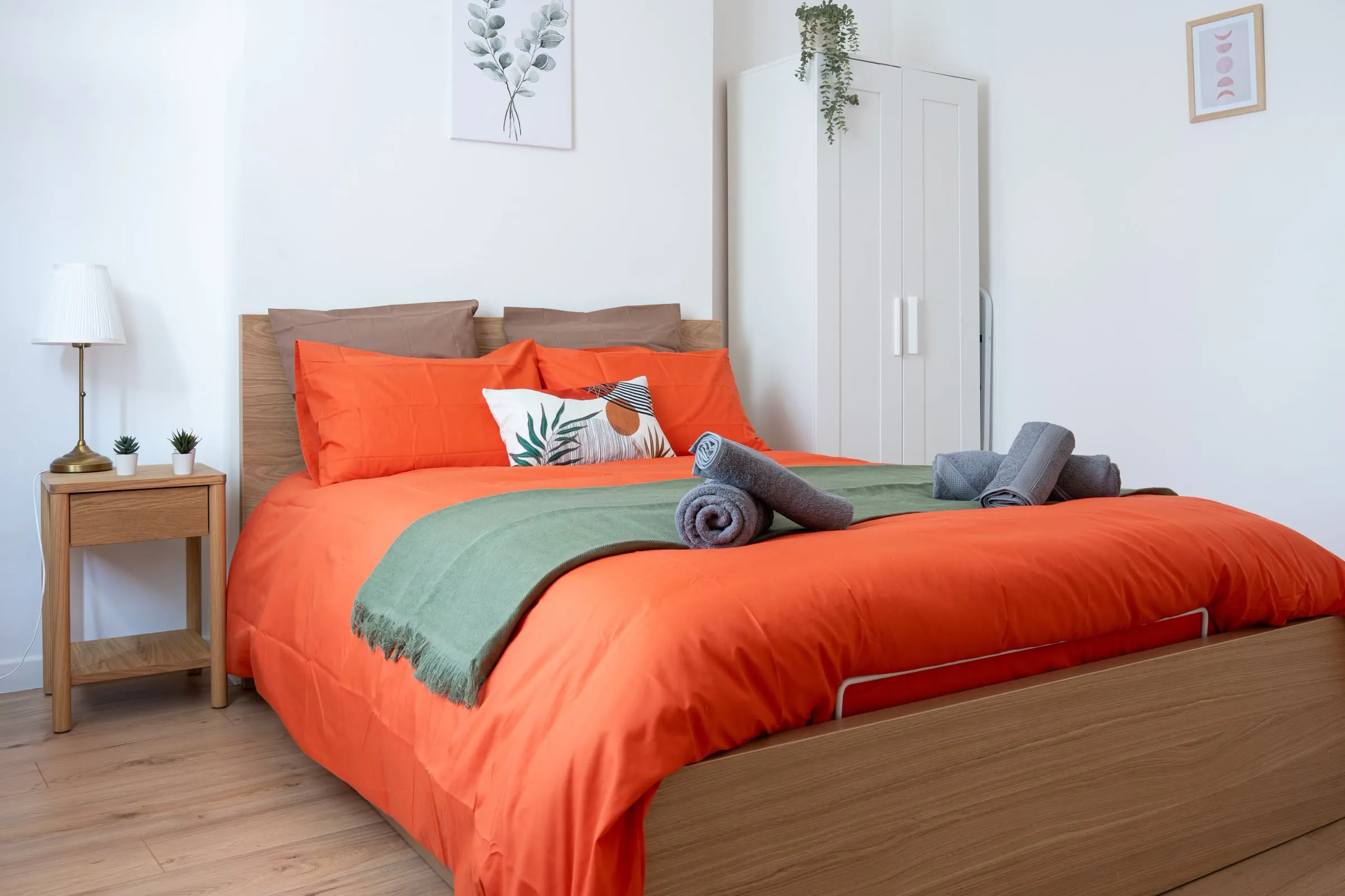 Chambre du Diderot à Lens, lit fait au linge orange et serviettes roulées pour les voyageurs
