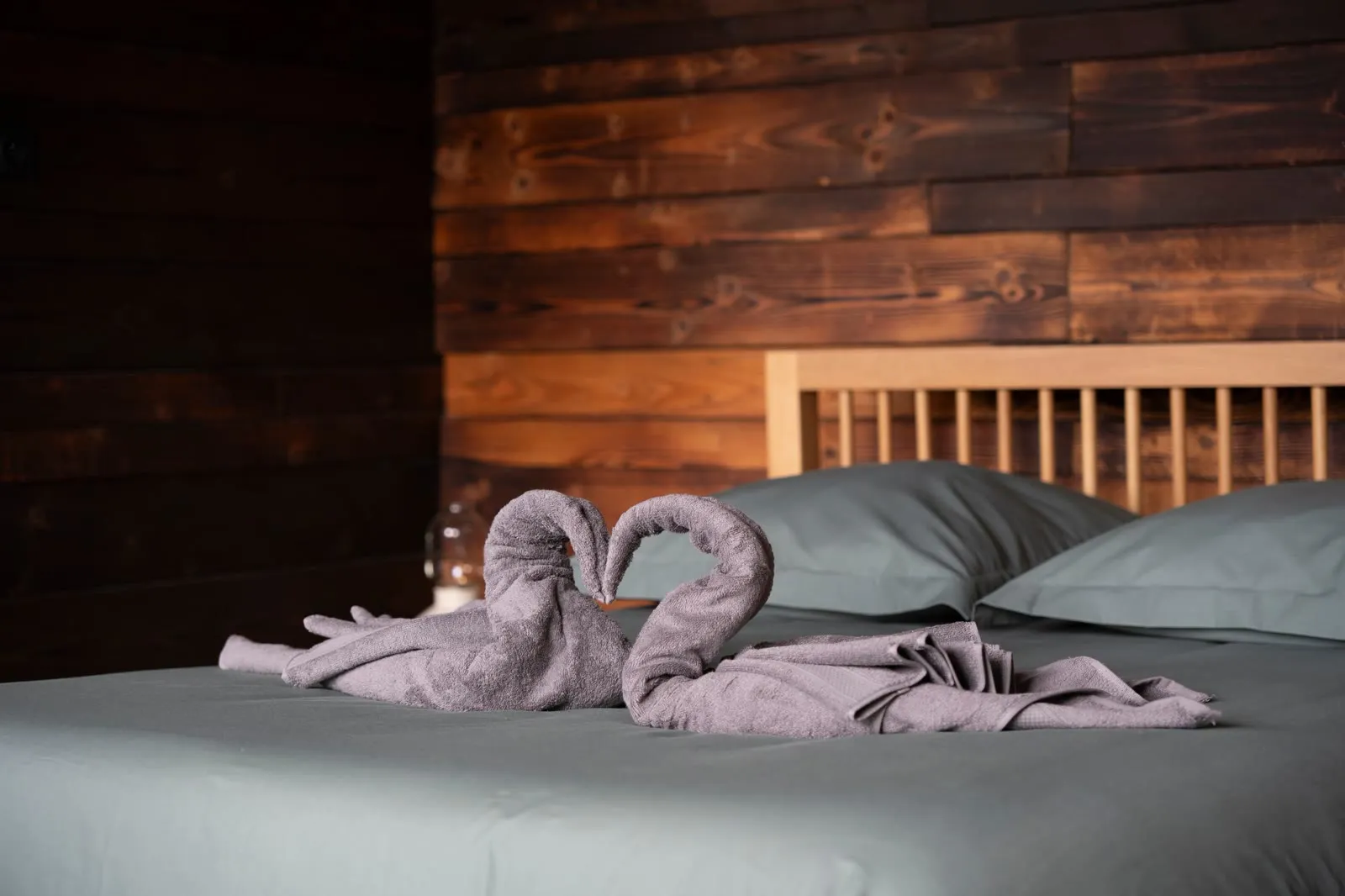 Lit au linge vert sauge et serviettes pliées en cygnes à La Cabane d'Alfred à Lens