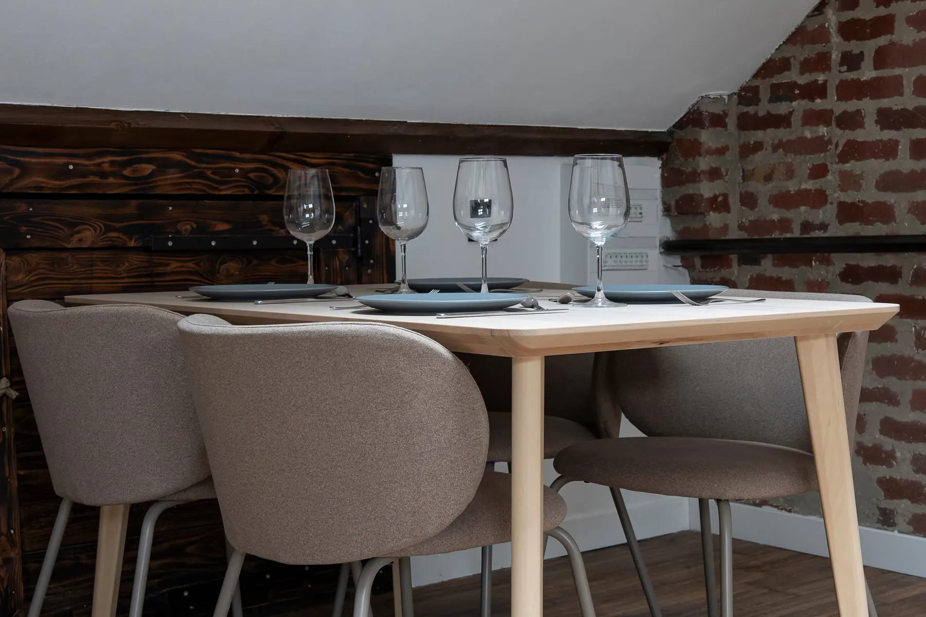 Coin repas du Loft d'Alfred à Lens, table dressée devant le mur de briques